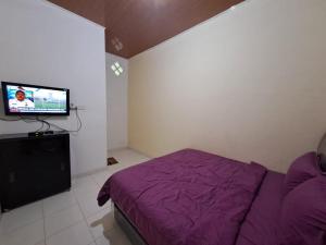 a bedroom with a purple bed and a flat screen tv at OYO 93714 Guest House Gembul Syariah in Jambi
