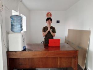 Ein Mann steht hinter einem Tisch mit erhobenen Händen. in der Unterkunft Capital O 93728 Guest House Cemara in Bandung