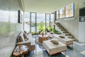uma sala de estar com sofás e uma escadaria com janelas em Casa Jenah em Darmasaba