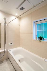 una vasca bianca in un bagno con finestra di 白キツネのおうち a Nagatsutachō