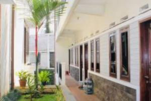 a building with a courtyard with a palm tree in it at Hotel O Qq Kost Near Pantai Kebesaran Beach in Laleng-balandae