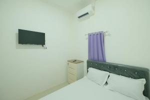 um quarto com uma cama e uma televisão na parede em OYO 93756 Qq Kost em Laleng-balandae