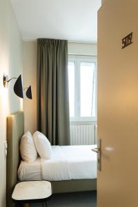 1 dormitorio con 1 cama, ventana y puerta en Grand Hotel de la Gare, en Angers