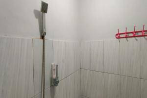 a shower with a hose attached to a wall at OYO 93752 Aglo Homestay in Rantau