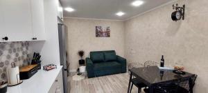 een woonkamer met een groene stoel en een tafel bij Apartment Rustaveli 118 in Koetaisi