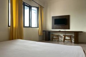 a bedroom with a bed and a desk with a television at OYO 93735 Pondok Zamzam in Pakato