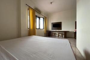 a bedroom with a white bed and a television at OYO 93735 Pondok Zamzam in Pakato