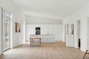 an empty white kitchen with a table and chairs at Brand New And Modern Summer House In Kulhuse in Jægerspris