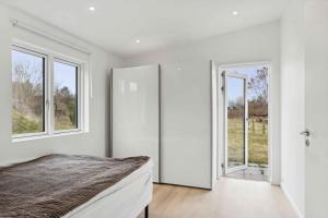 a bedroom with white walls and windows and a bed at Brand New And Modern Summer House In Kulhuse in Jægerspris