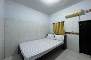 a small bed in a room with a yellow curtain at OYO 93753 Rafira Losmen in Rantau