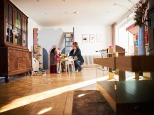 Eine Frau, die mit einem kleinen Mädchen im Wohnzimmer spielt. in der Unterkunft Familyhaus Hochreuther's Hof in Oberdachstetten
