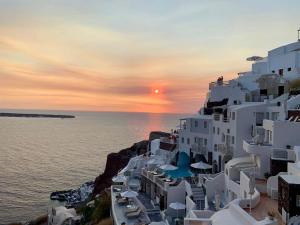 a group of white buildings on the side of the ocean at ArmonOia Luxury Caves in Oia
