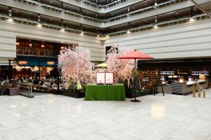 un gran vestíbulo con árboles rosas en un edificio en Kyoto Brighton Hotel en Kyoto