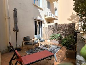 une terrasse avec une table, des chaises et un parasol dans l'établissement Nyx Hôtel Indépendant, à Perpignan