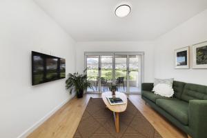 ein Wohnzimmer mit einem grünen Sofa und einem Tisch in der Unterkunft Mountain facing 2 bedroom apartment in Kapstadt