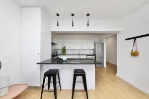 a kitchen with white cabinets and black counter stools at Mountain facing 2 bedroom apartment in Cape Town