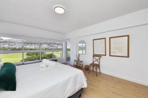 a white bedroom with a large bed and large windows at Mountain facing 2 bedroom apartment in Cape Town
