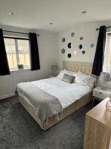 a bedroom with a large white bed and two windows at Cathedral Apartment in Lichfield
