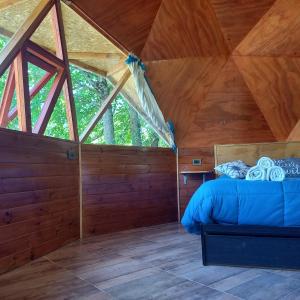 ein Schlafzimmer mit einem Bett in einer Holzhütte in der Unterkunft Puelo EnDomos in Lago Puelo