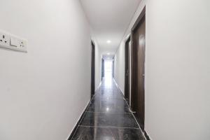 a hallway with white walls and black doors at FabExpress Roadway Inn in New Delhi