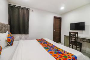 a bedroom with a bed and a desk and a television at FabExpress Super 8 Residency in New Delhi