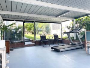 a patio with a gym with chairs and a treadmill at Your home at Cockle Bay in Auckland