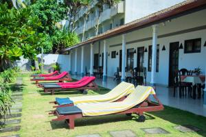 a row of chaise lounges on the grass near a building at Ocean of Life Ayurveda Hotel in Induruwa