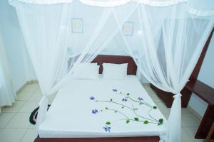 a bed with white sheets and blue flowers on it at Ocean of Life Ayurveda Hotel in Induruwa