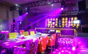 巴雷利Hotel Swarn Towers的餐厅拥有粉红色的灯光和桌椅