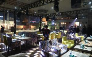 a restaurant with tables and chairs and people in the background at Hotel Swarn Towers in Bareilly