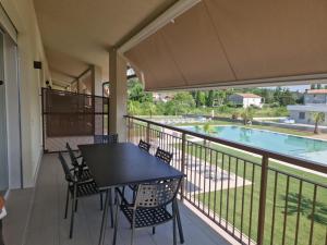 un balcone con tavolo, sedie e piscina di Residence La Magnolia - Aparments a Lazise