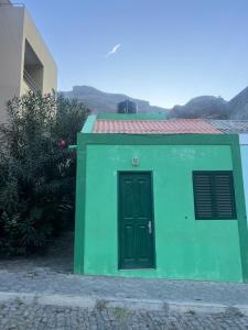 een groen gebouw met een deur in een tuin bij Casa Medina in Fajãzinha
