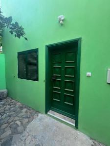 een groen gebouw met een deur en een raam bij Casa Medina in Fajãzinha