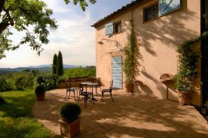 un patio con mesa y sillas frente a una casa en Podere Le Murella, en Palaia