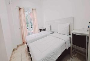 a white bedroom with two beds and a window at TOS Residence Near Gading Serpong in Kampung Sawah
