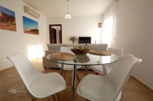 sala de estar con mesa de cristal y sillas blancas en Hacienda Laguna Seca - Apart. Lavanda, en Chiclana de la Frontera