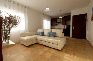 a living room with a white couch and a kitchen at Hacienda Laguna Seca - Apart. Lavanda in Chiclana de la Frontera