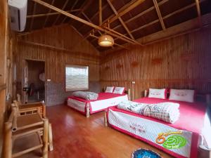 Una habitación con tres camas en una habitación de madera. en Đảo Chè Thanh Chương - Homestay Gió Lào, en Trai Ðỏ