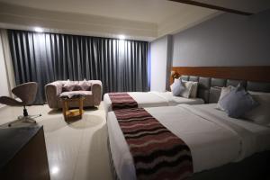 um quarto de hotel com duas camas e uma cadeira em Eastin Hotels em Hyderabad