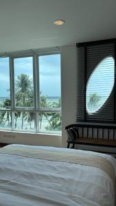 a bedroom with a bed and a window with palm trees at The Beach Bangsaen by Thanthita next to Wonnapa beach in Bangsaen