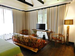 een slaapkamer met een bed en een tv en een bank bij Baan Saen Fang Chiang Mai - SHA Plus in Chiang Mai