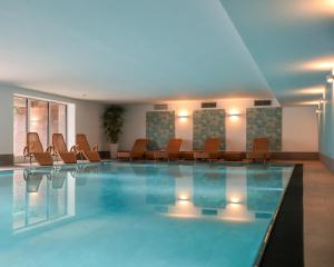a pool in a hotel with chairs and tables at Appartement-Hotel Timmendorfer Strand in Timmendorfer Strand