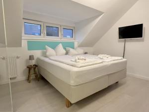 Schlafzimmer mit einem Bett, einem TV und Fenstern in der Unterkunft 3SZ Penthaus Luna am Sandstrand mit Meerblick & Balkon in Lübeck