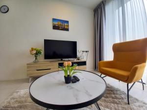 een woonkamer met een tafel, een stoel en een televisie bij Cozy Home at Near Centre and Airport @ Galacity in Kuching