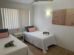 a bedroom with two beds and a window at Beachfront at Silver Sands Hervey Bay in Hervey Bay