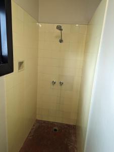 ein Bad mit einer Dusche und weißen Fliesen in der Unterkunft GRAND CENTRAL HOTEL PROSERPINE in Proserpine