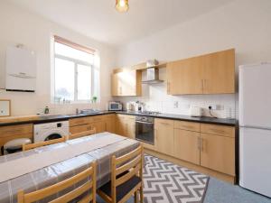 a kitchen with wooden cabinets and a white refrigerator at Pass the Keys Spacious 3 Bed Flat Near Kings Cross and Camden in London