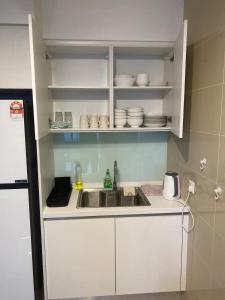 uma cozinha com um lavatório e armários brancos em Sentral Suites KL Sentral by NomadNest em Kuala Lumpur