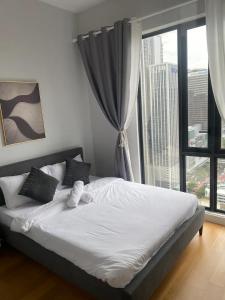 uma cama num quarto com uma grande janela em Sentral Suites KL Sentral by NomadNest em Kuala Lumpur