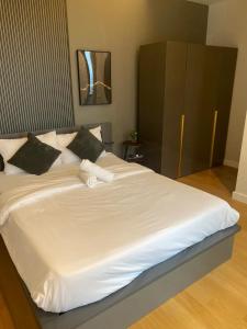 um quarto com uma grande cama branca com almofadas pretas em Sentral Suites KL Sentral by NomadNest em Kuala Lumpur